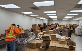 Group of people packing boxes at a volunteer event.