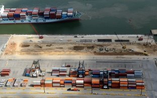Aerial view of the site during construction with a ship on the water in the background