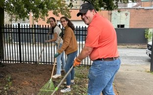 Three people raking leaves and dirt