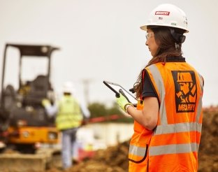 Person holding a tablet on jobsite.