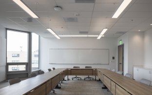 Classroom with long rectangular tables and chairs.