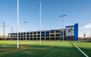 An athletic field with parking garage in the background.