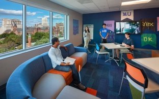 People enjoying a common area on a couch and table and chairs.