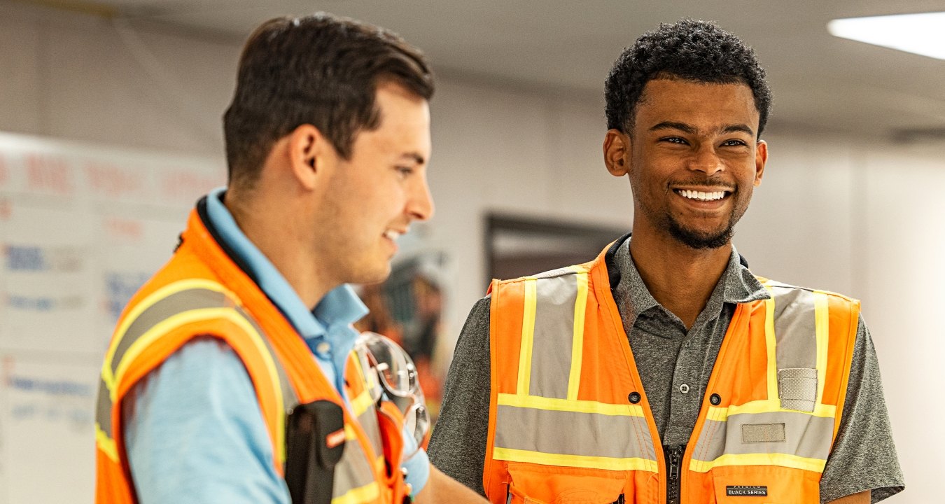 Two people talking while wearing safety vests