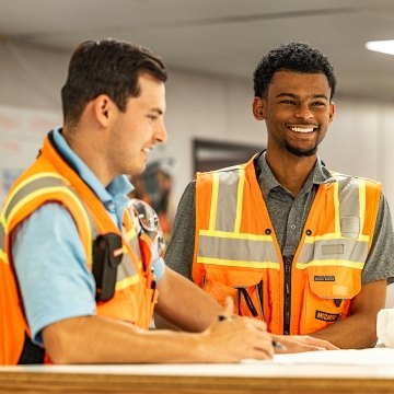 Two people talking while wearing safety vests